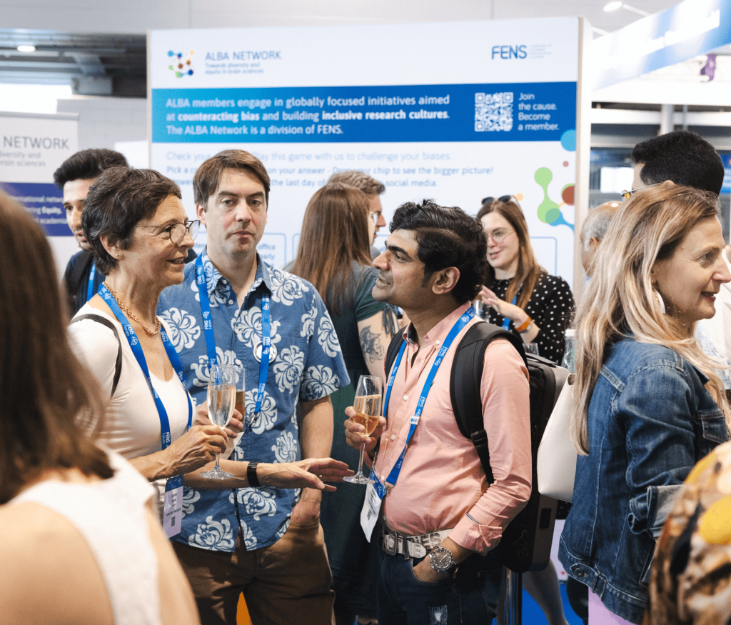 3 people discuss in a crowd. they hold a glass of bubbly wine. on the left a person with a white top, on the right, a person with a salmon shirt. in the middle someone with a blue shirt with white prints.